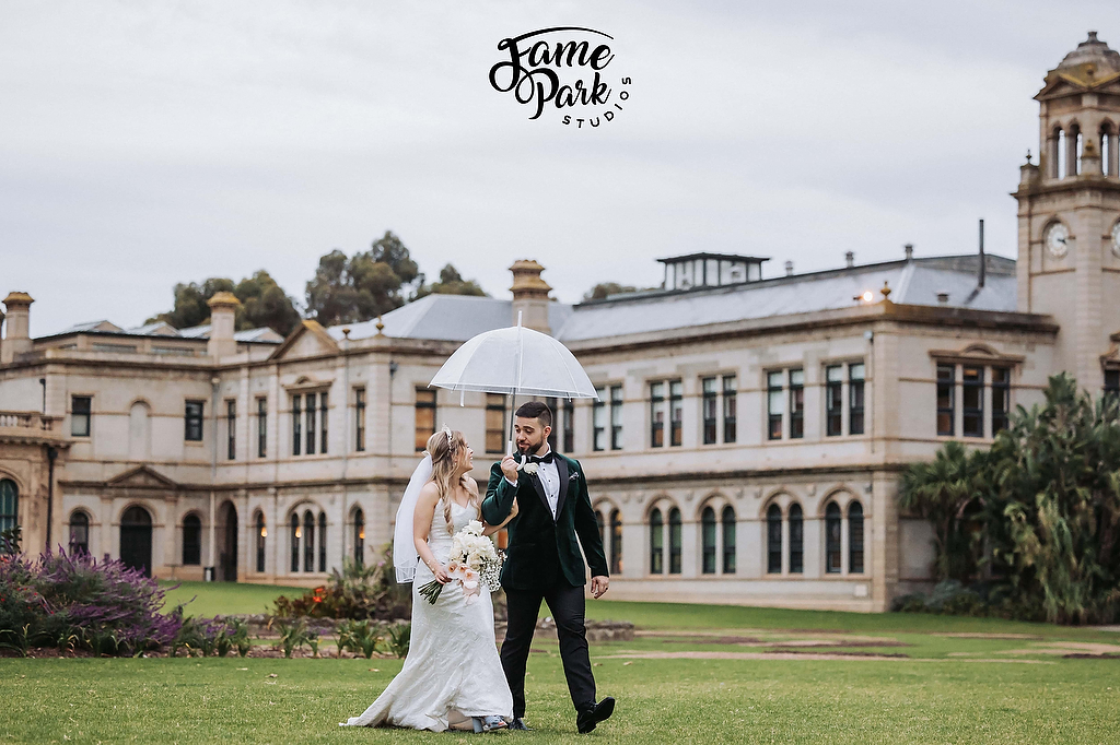 The bride and groom walking in the rain at Werribee Park