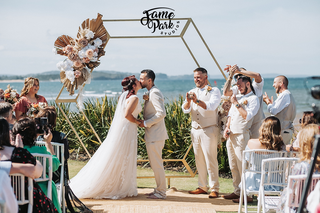 The bride and groom are having their first kiss as a husband and wife on palm beach