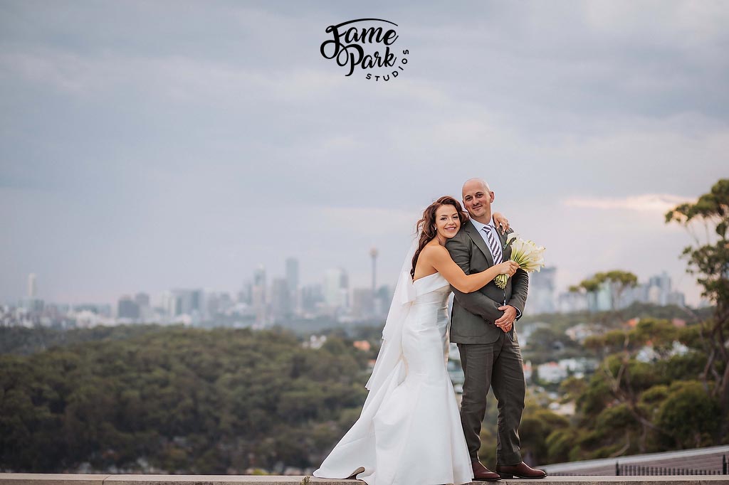 The couple is holding each other with a Sydney city background