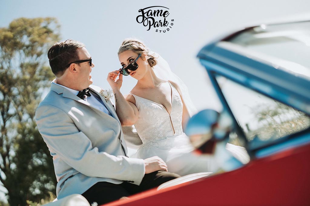 The bride and groom are sitting on a car and looking at each other.
