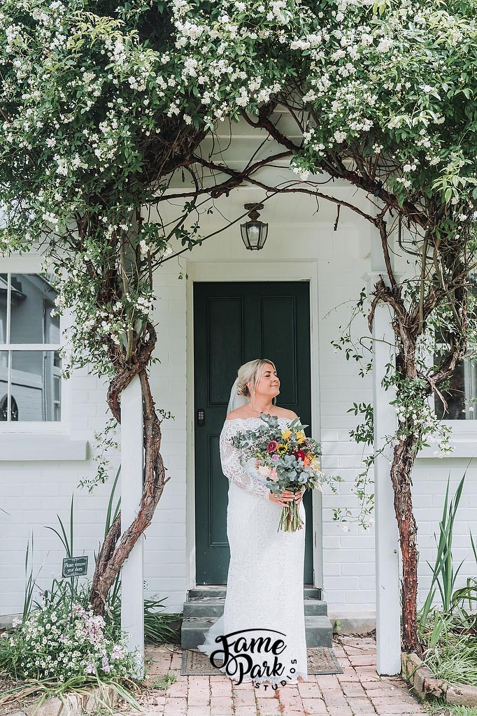 The bride is standing in front of her little farm house