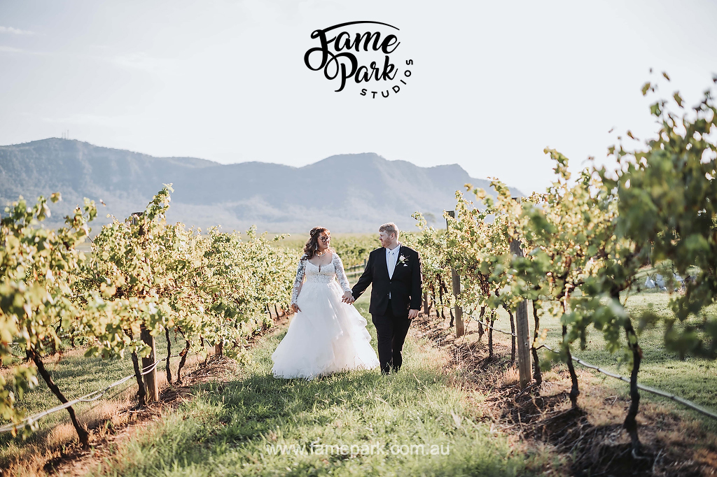The bride and groom holding their hands and walking in the Vineyard