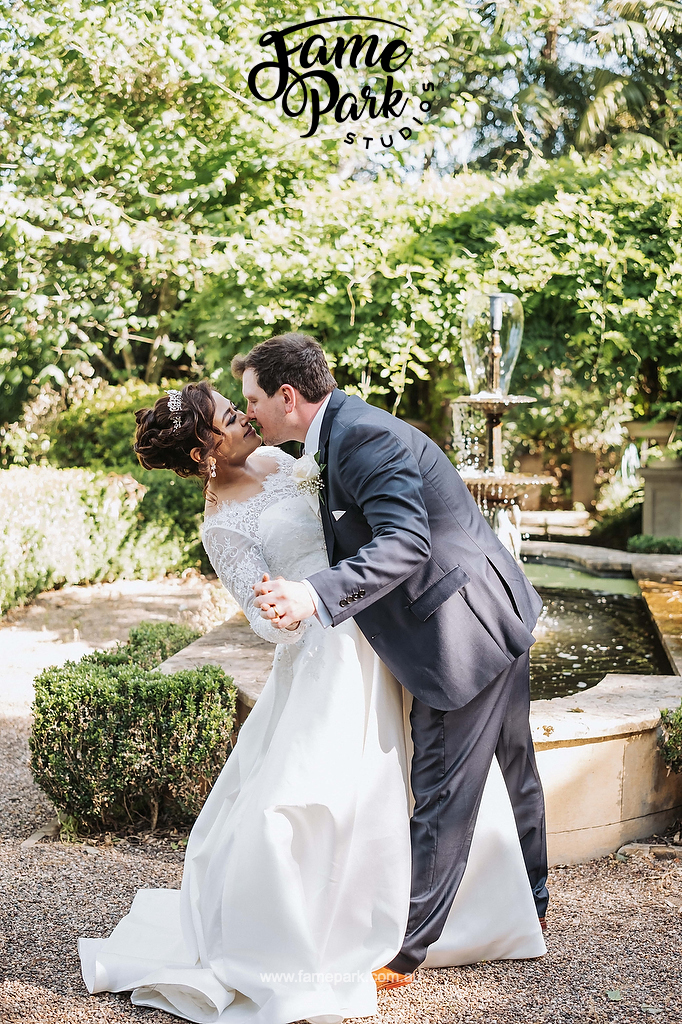 The newlyweds kissing in front of a fountain in Hunter Valley Garden