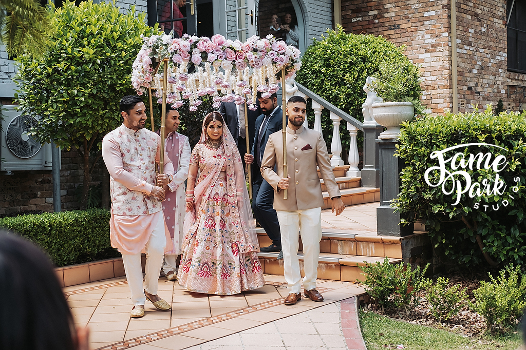 The bride and her family are walking to her Indian wedding ceremony