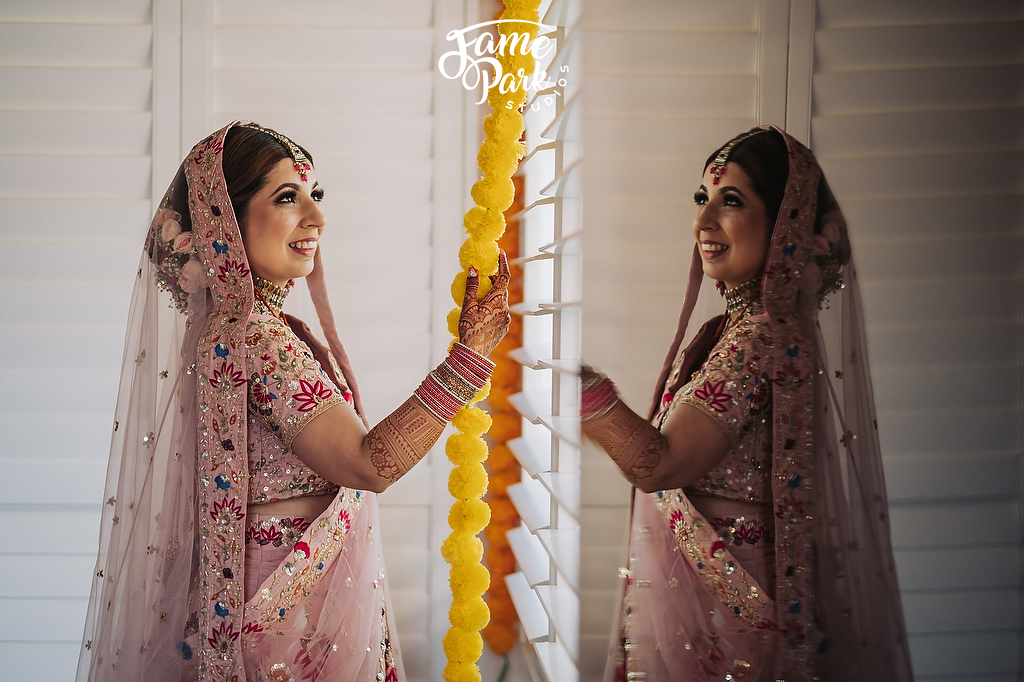An Indian bride is looking at the yellow decoration near a mirror