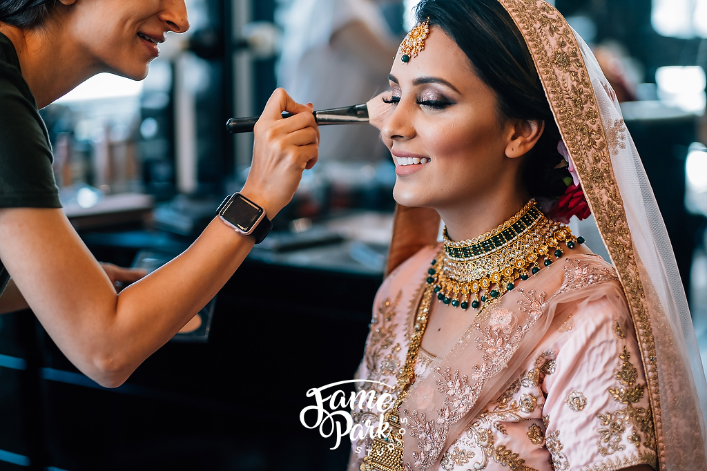 The make up artist is finishing the touch up for the bride