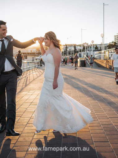 The beautiful bride in a simple wedding dress is walking with groom on the beachside.