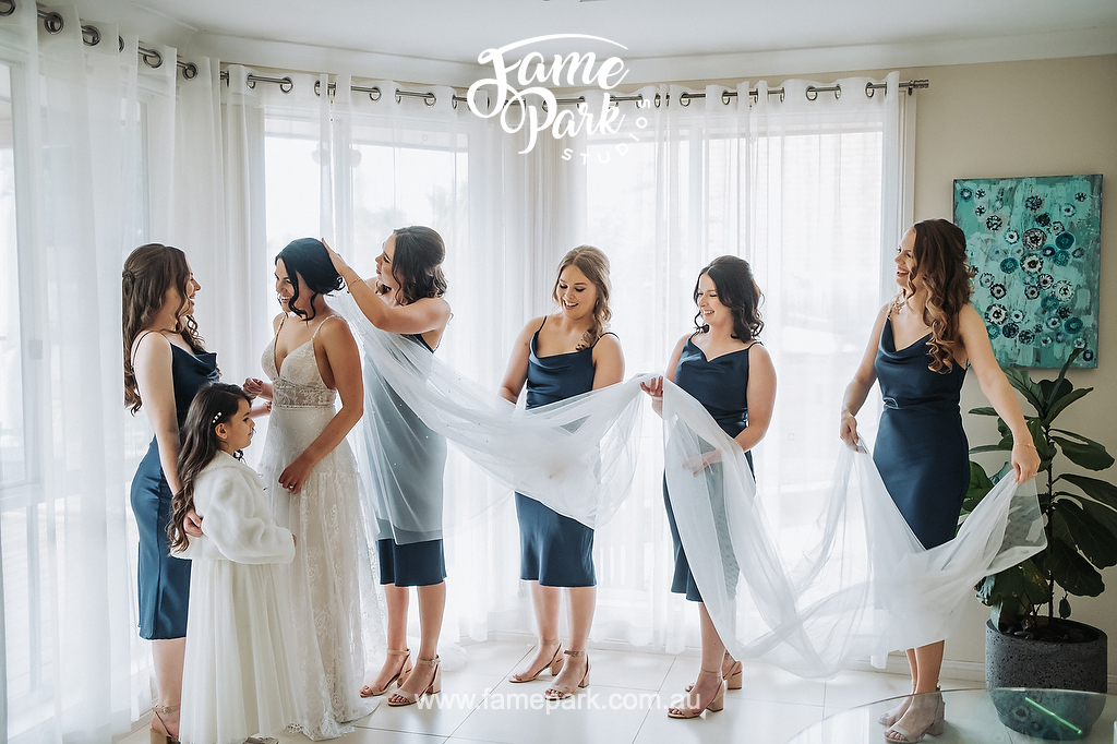 The bridesmaids are helping the bride to put on her wedding dress