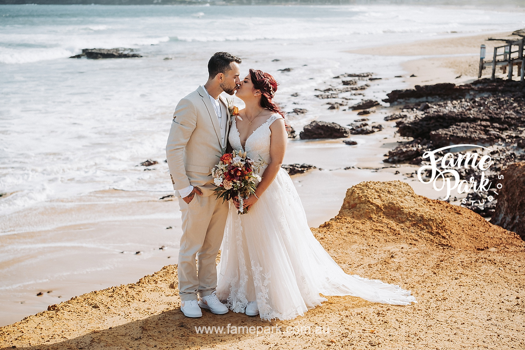 The bride and groom kissing on the beach