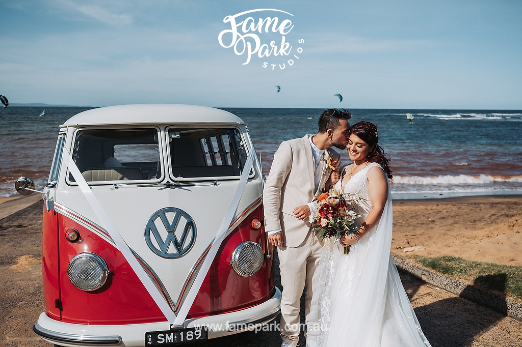 The beautiful couple has their photo with a classic kombi on beach