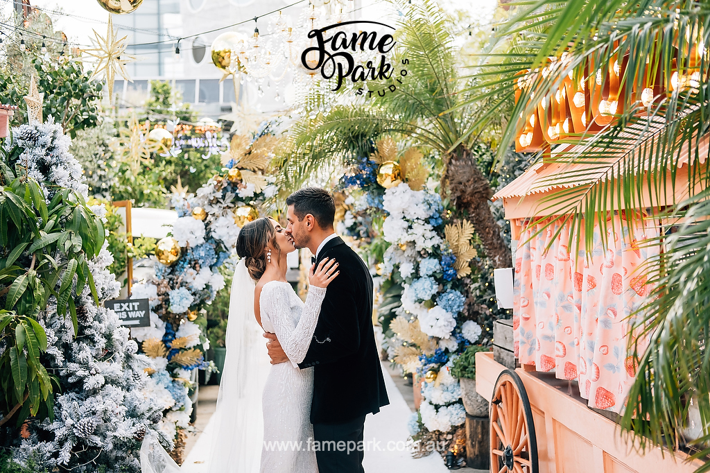 The bride and groom kissing in front of a floral backdrop