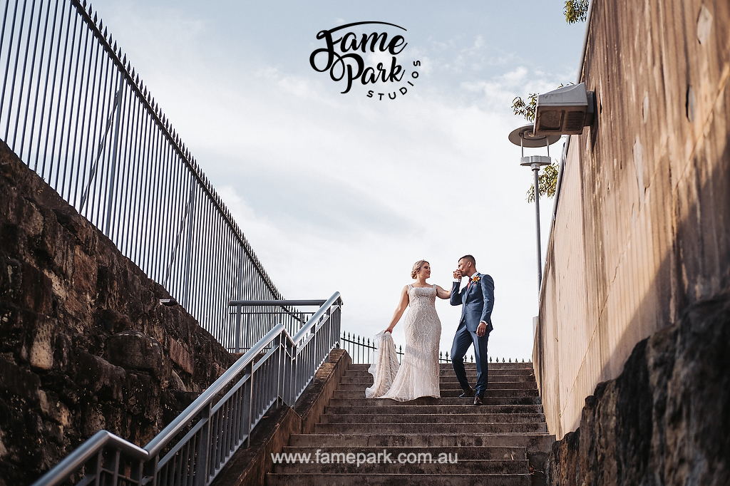 The groom kissing the bride’s hand on a stair near Sydney CBD