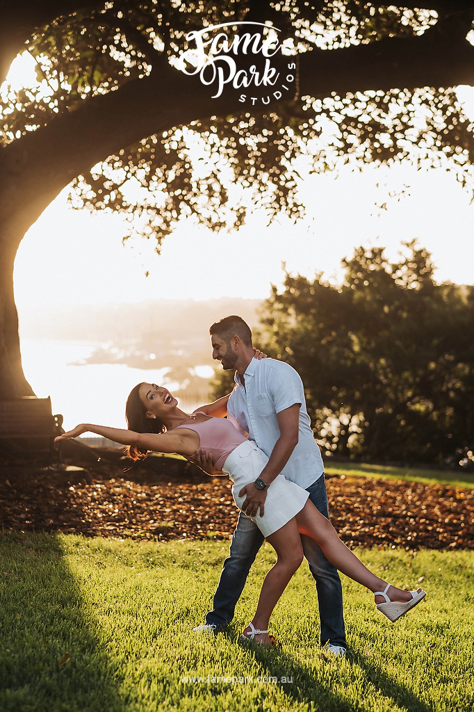 The couple dancing under a tree during sunset hour