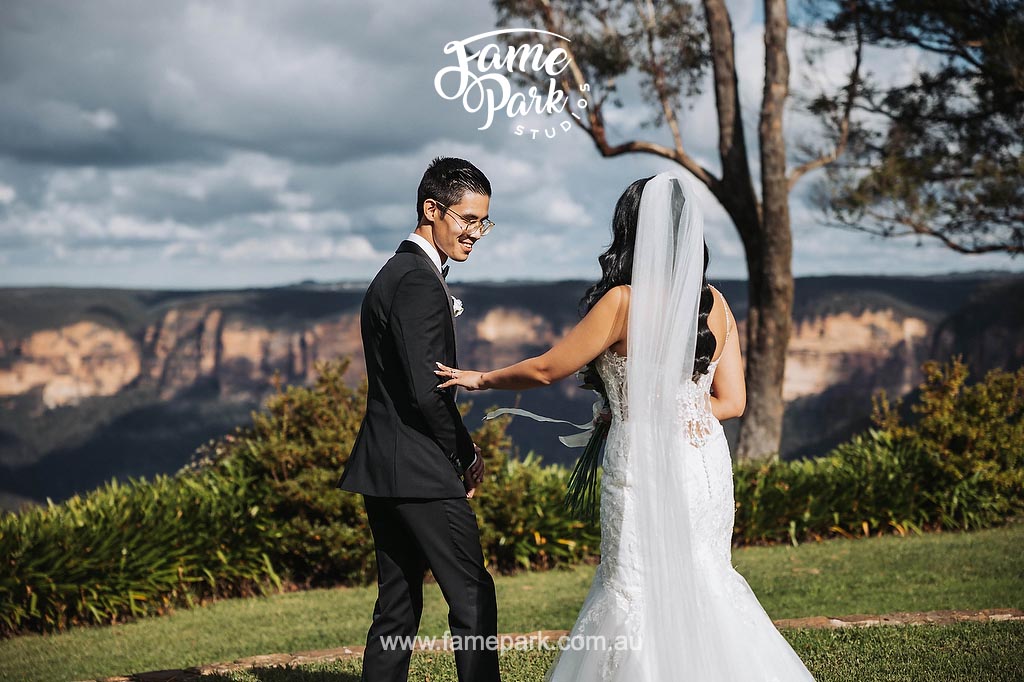 The bride and groom stand in awe as they have their first look at the breathtaking Blue Mountains, their eyes filled with wonder and admiration for the majestic landscape surrounding them.