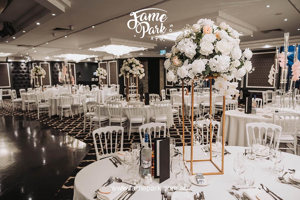 A beautifully arranged reception hall with elegant floral centerpieces, soft ambient lighting, and delicate lace table runners, creating a romantic and enchanting atmosphere.