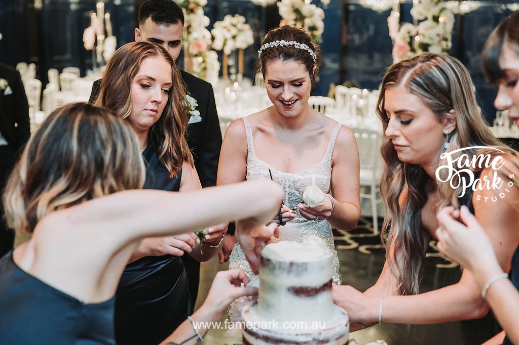 The bride adds a personal touch to her wedding cake, delicately placing handmade sugar flowers on each tier, showcasing her creativity and attention to detail.