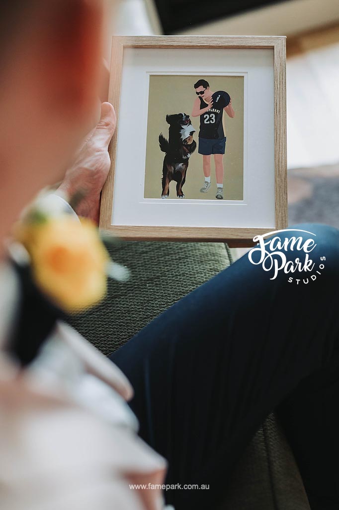 A man holding a framed picture of a dog and a football player.