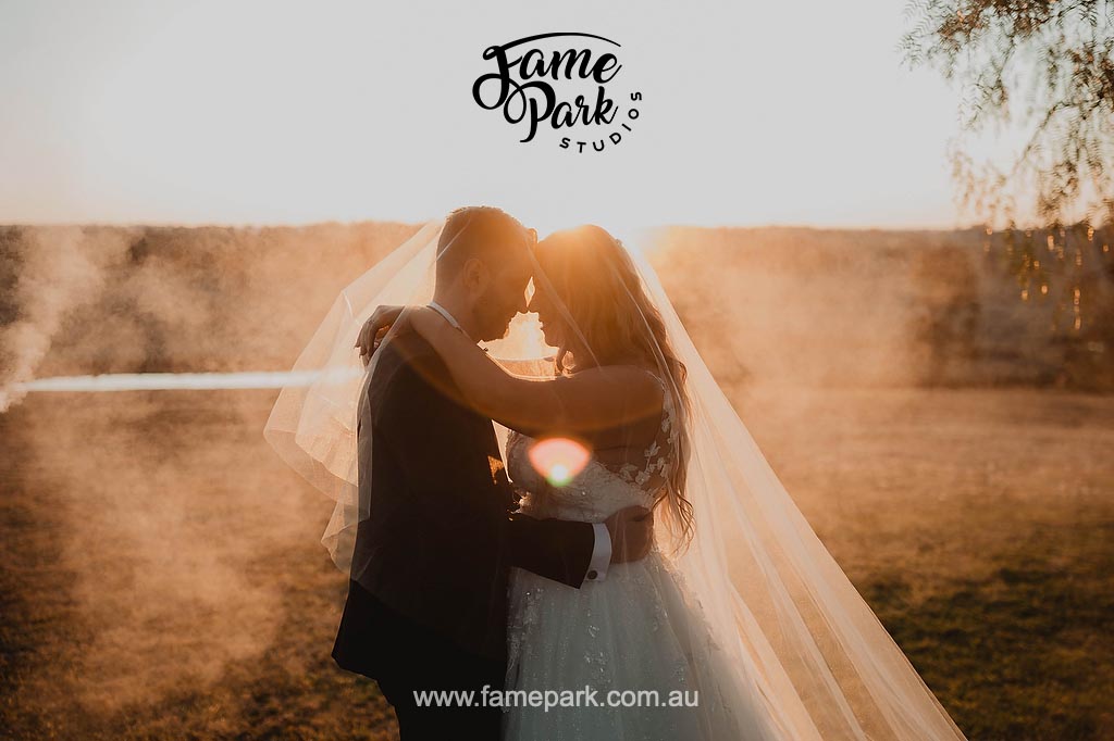 A bride and groom embrace during their wedding reception at a misty field in Western Sydney.