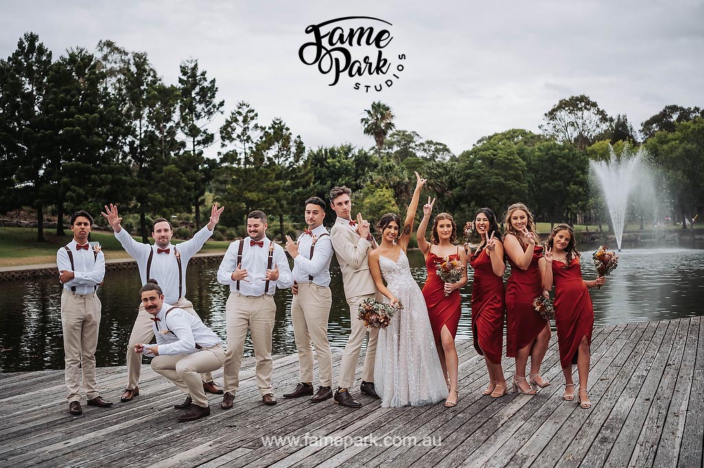 A group of bridesmaids and groomsmen posing on a wooden deck at nurragingy reserve.