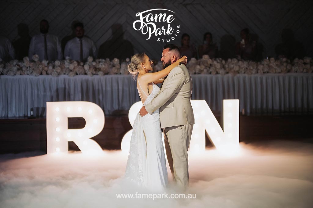 A bride and groom share a romantic kiss during their first bridal dance surrounded by dry ice over the floor