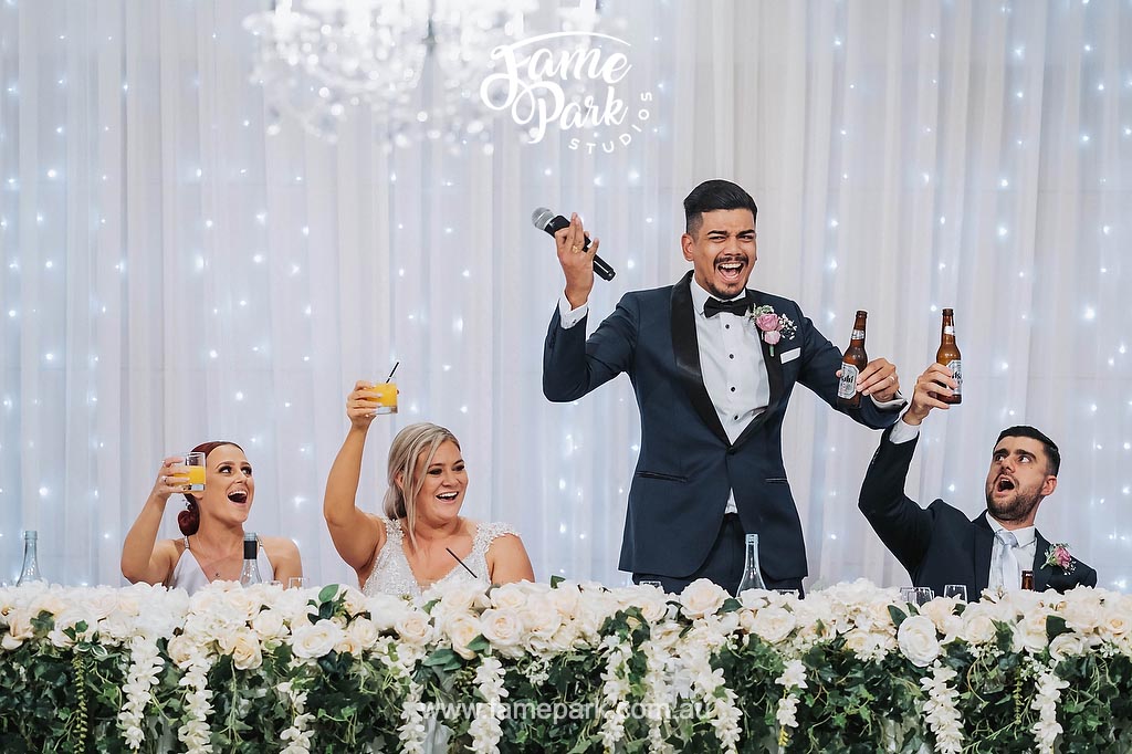 A man in a tuxedo is toasting the newlyweds at a lavish wedding reception