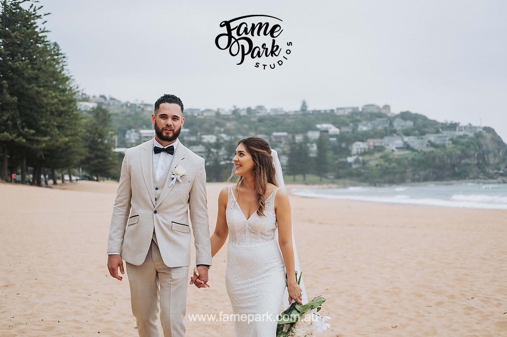 A bride and groom strolling along the beach at Bondi Beach, one of the stunning wedding venues on the Northern Beaches.