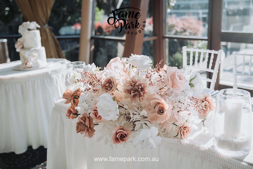 A white table adorned with flowers, serving as a wedding centrepiece.