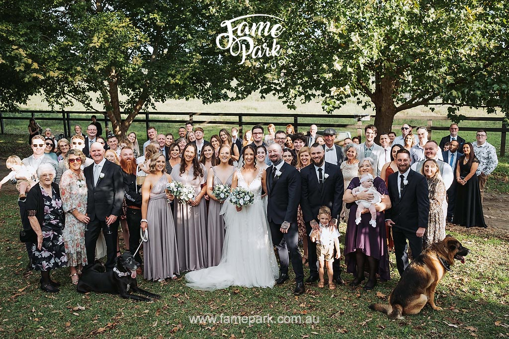 A fun wedding party posing for a unity-filled photo in front of a tree.