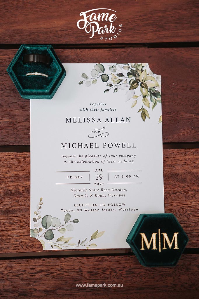 A wedding invitation featuring green leaves and a ring.
