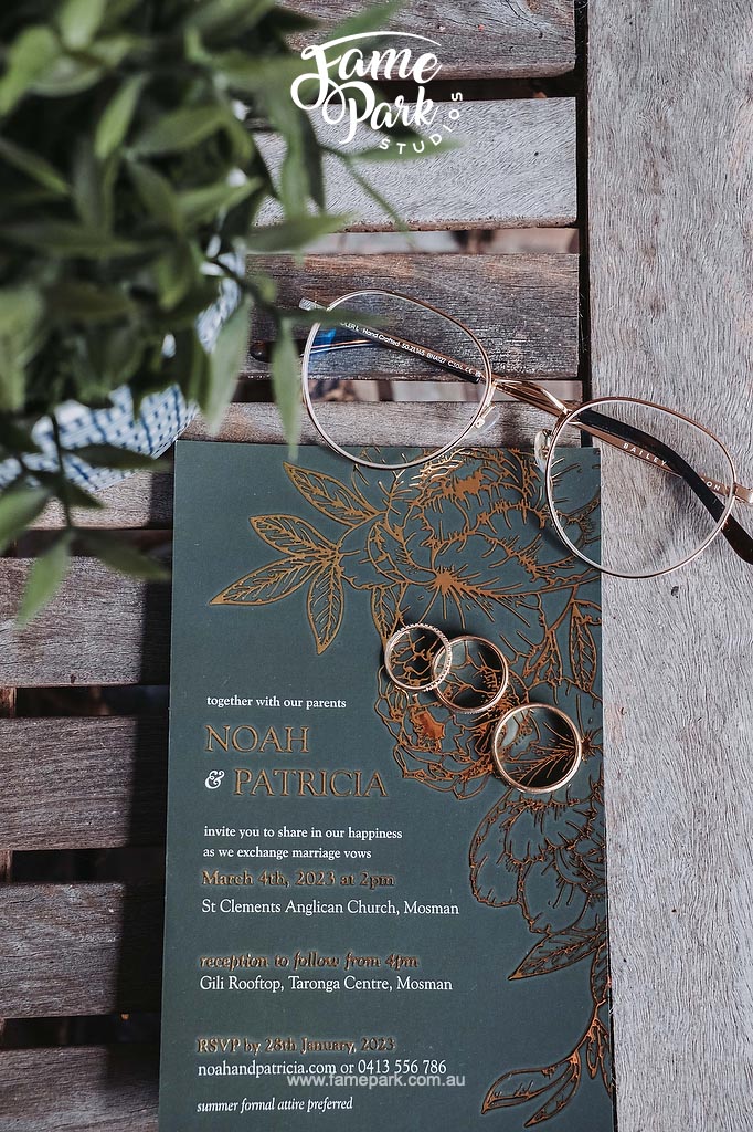Wedding invitation design ideas featuring rings and glasses on a wooden table.